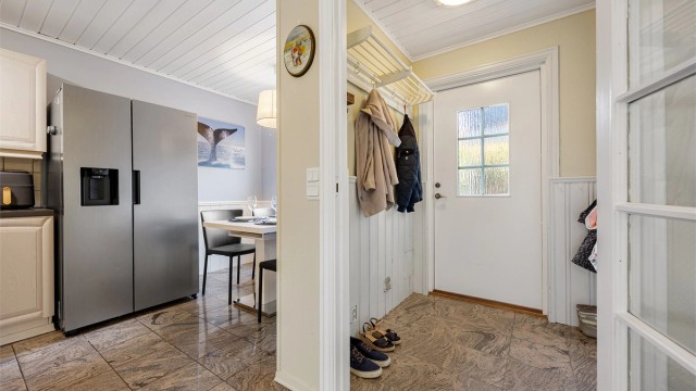 Kjøkkenet har åpen passasje mot gangen og plass til spisebord ved vinduet.