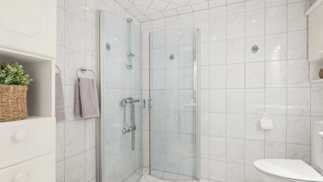 Badet er utstyrt med dusjhjørne med innfellbare dører og mekanisk avtrekk.