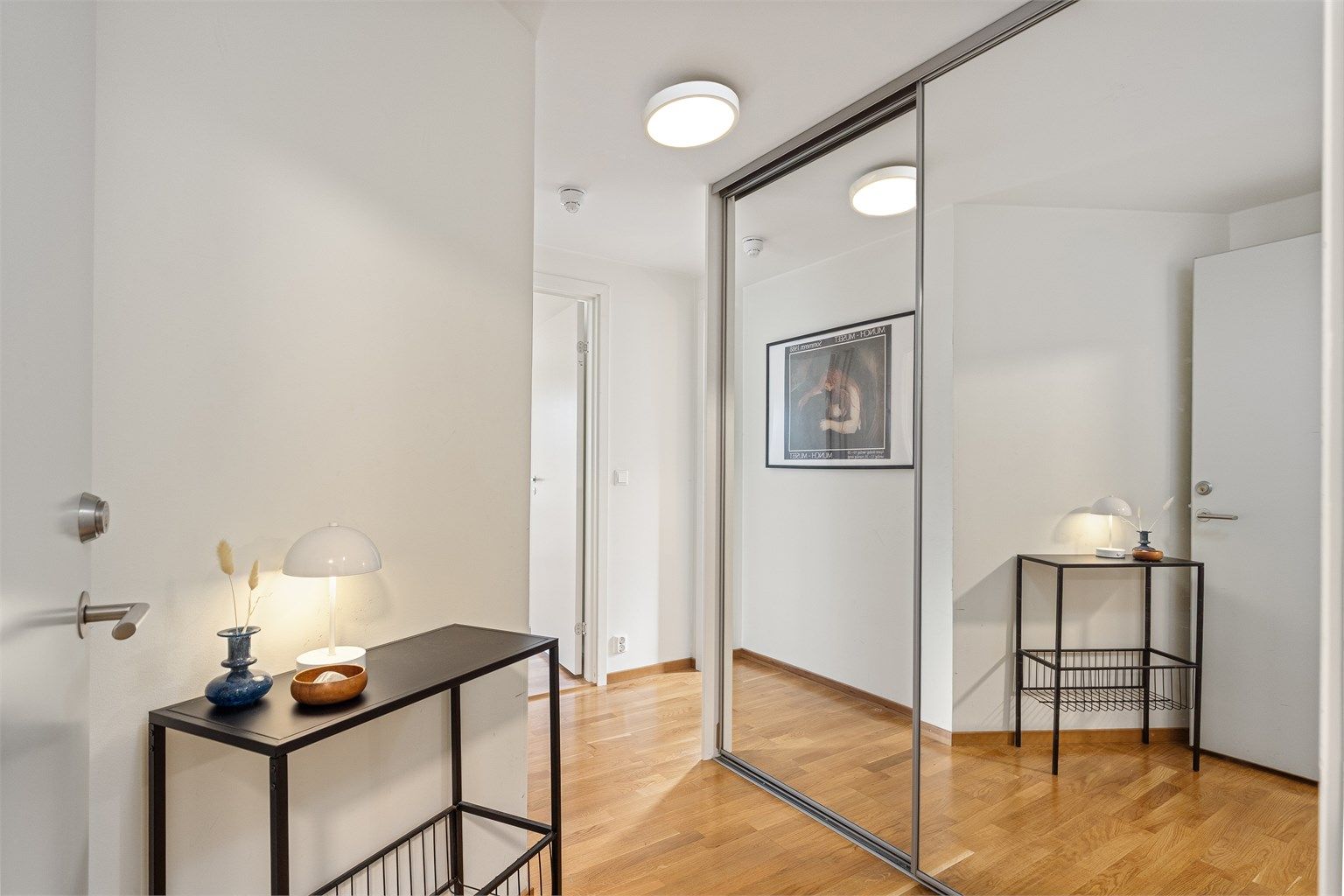 Entré med parkett på gulv og skyvedørsgarderobe med speildører til yttertøy og sko.