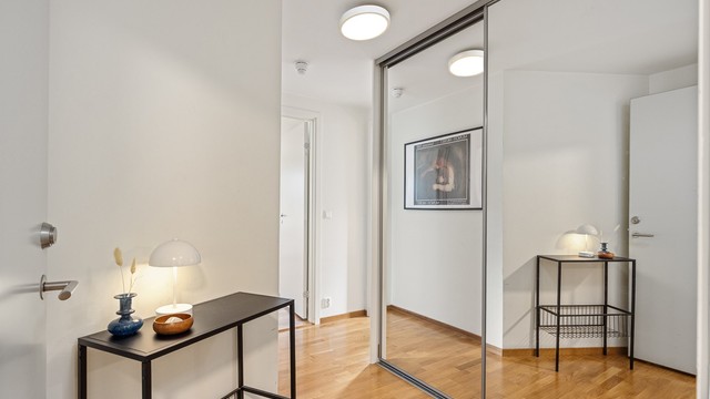 Entré med parkett på gulv og skyvedørsgarderobe med speildører til yttertøy og sko.