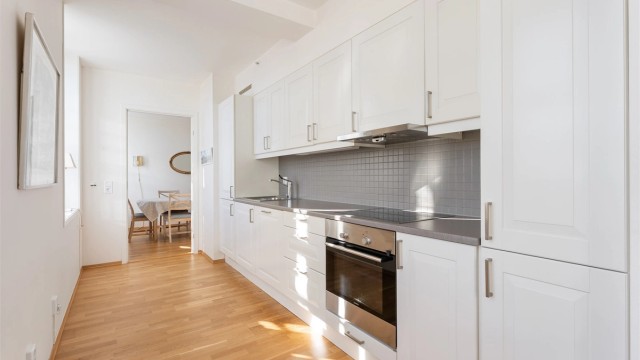 Kjøkkeninnredningen har profilerte fronter og integrerte hvitevarer.