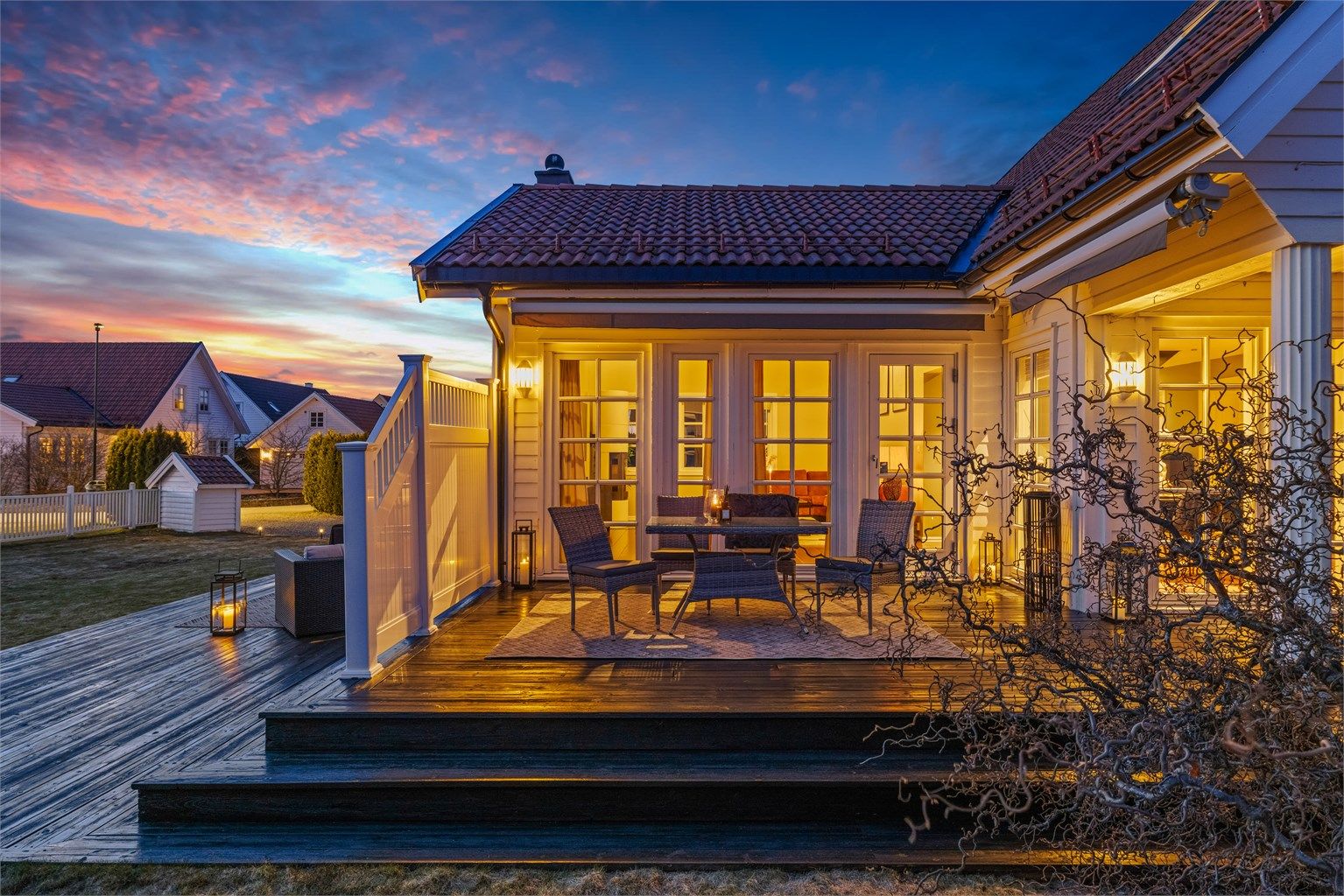 Utsyn over hagen og terrassen etter solnedgang.