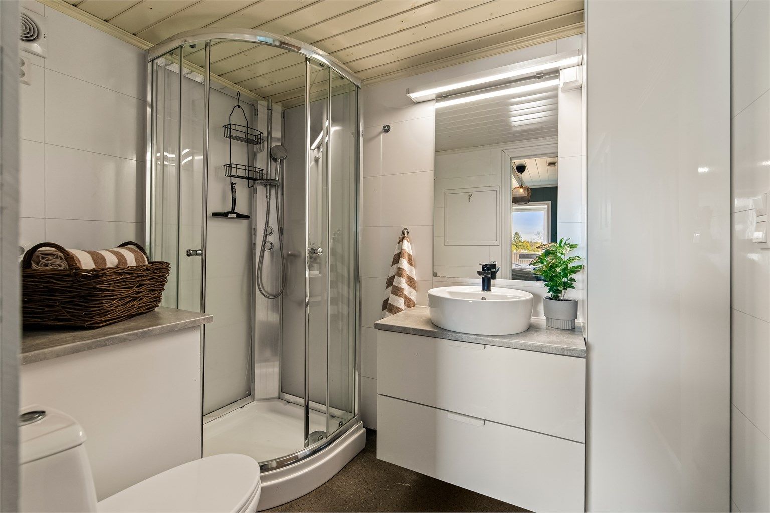 Badet har vegger med våtromsplater, gulvbelegg og opplegg for vaskemaskin.