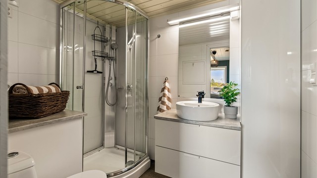 Badet har vegger med våtromsplater, gulvbelegg og opplegg for vaskemaskin.