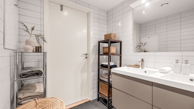 Innredet med heldekkende dobbelservant, vegghengt toalett og badekar.