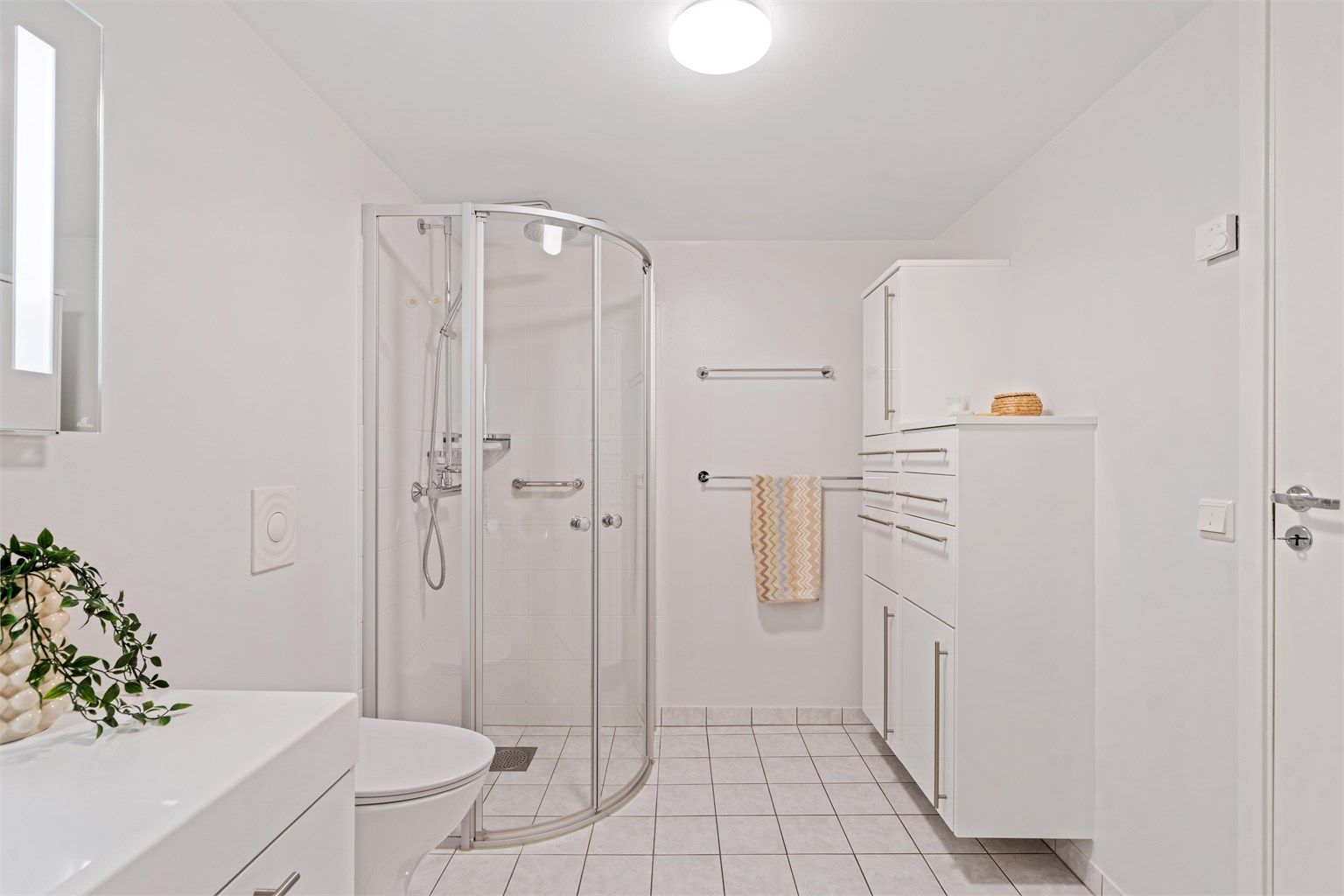 Bad med vegghengt servantmøbel, speil med belysning og vegghengt toalett.