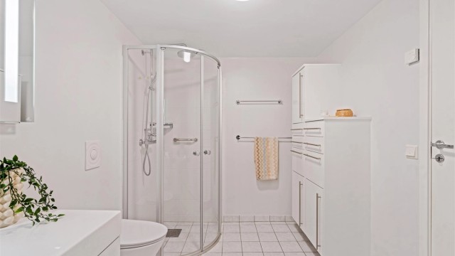 Bad med vegghengt servantmøbel, speil med belysning og vegghengt toalett.