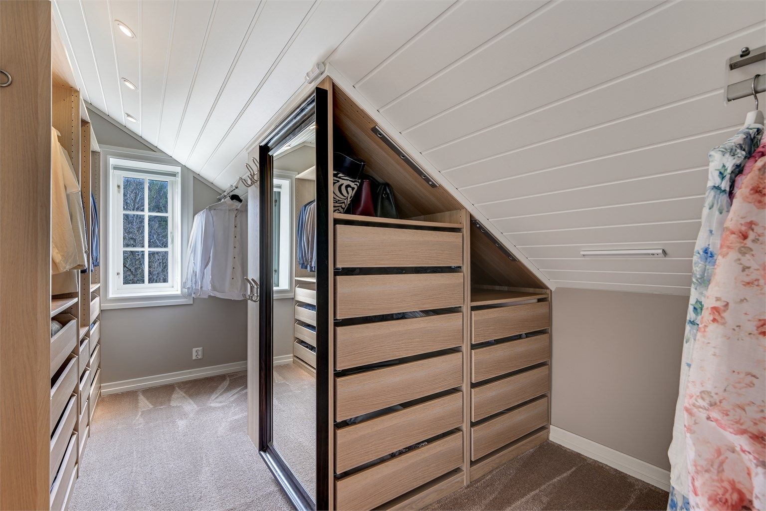 Omkledningsrommet er innredet med en smart garderobeløsning som utnytter plassen under skråtaket optimalt.