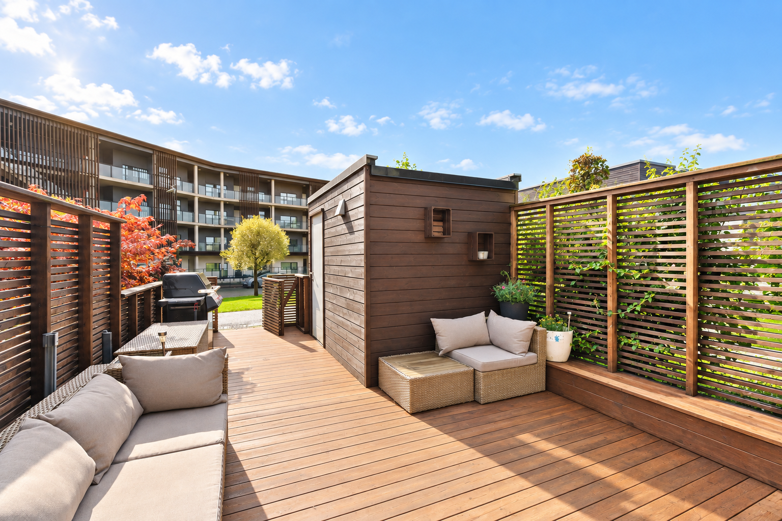 Romslig markterrasse med terrassebord i tre, skjermet av levegg og god plass til utemøbler. God utvendig bod