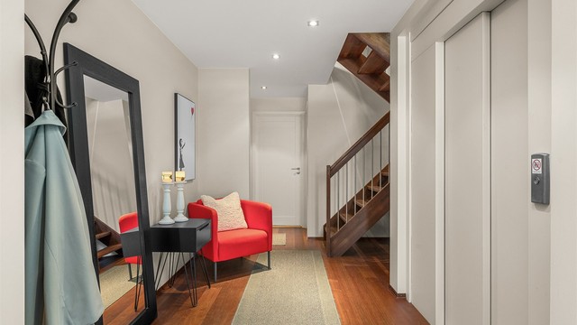 Gangen oppleves romslig og innbydende, med god flyt mellom etasjene og praktiske kvaliteter som både heis og trapp – løsning som gjør boligen ekstra komfortabel i hverdagen.