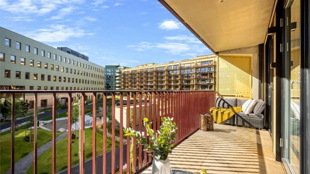 Moderne leilighet fra 2026 med heisadkomst og balkong med utsyn mot fellesområdet. Foto: Martine Eren Studio