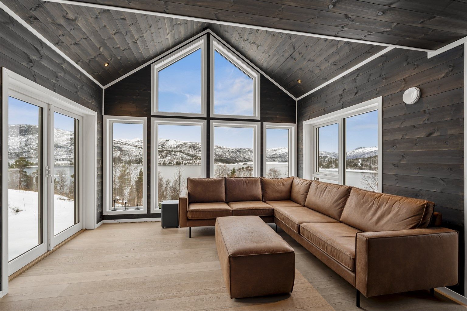 Moderne og koselig hytte med panel på vegger og tak og åpen himling i stuen 