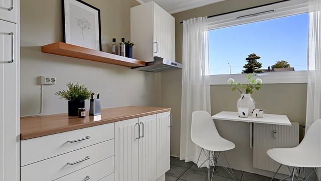Kjøkkenet har en smart, vegghengt spiseplass ved vinduet.
