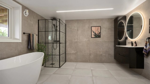 Badet har flislagt gulv med gulvvarme og et romslig dusjhjørne med glassdører.