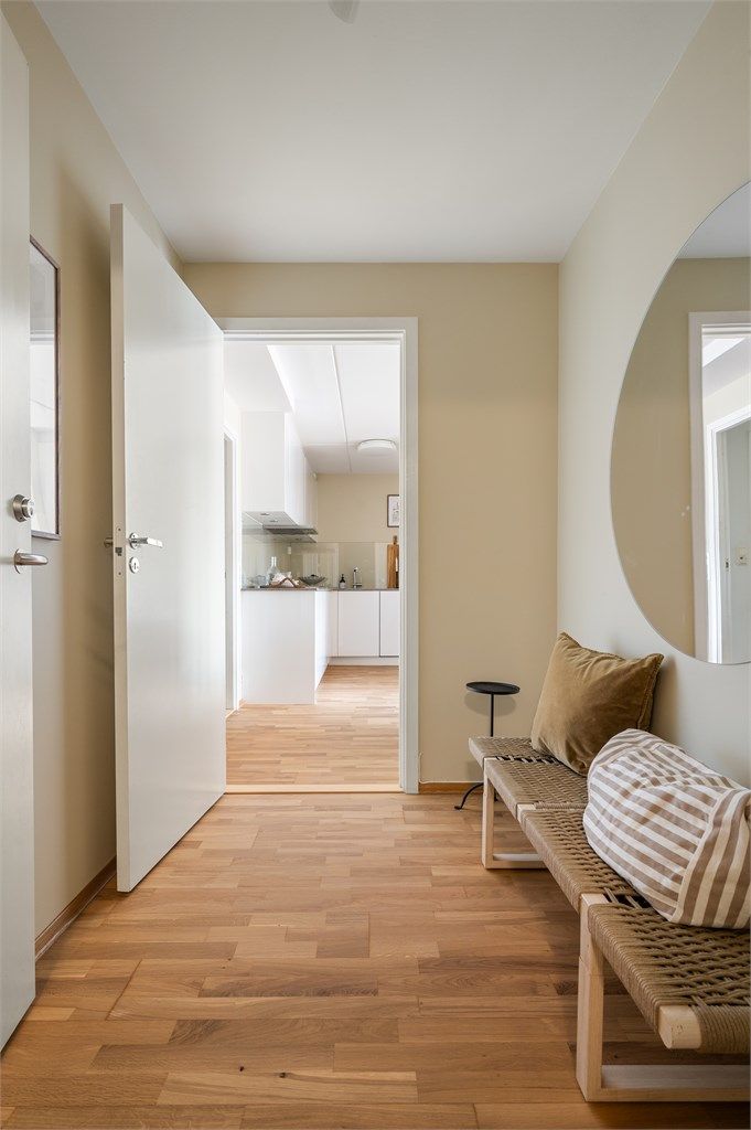 Velkommen inn! Den lyse entréen gir et elegant førsteinntrykk, hvor duse fargetoner og en gjennomført materialpalett skaper en rød tråd videre gjennom boligen.