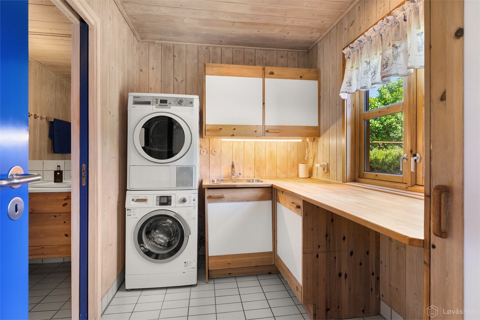 Praktisk vaskeromsdel i tilknytning til badet, med heltre benkeplate og opplegg for vaskemaskin og tørketrommel