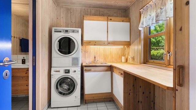 Praktisk vaskeromsdel i tilknytning til badet, med heltre benkeplate og opplegg for vaskemaskin og tørketrommel