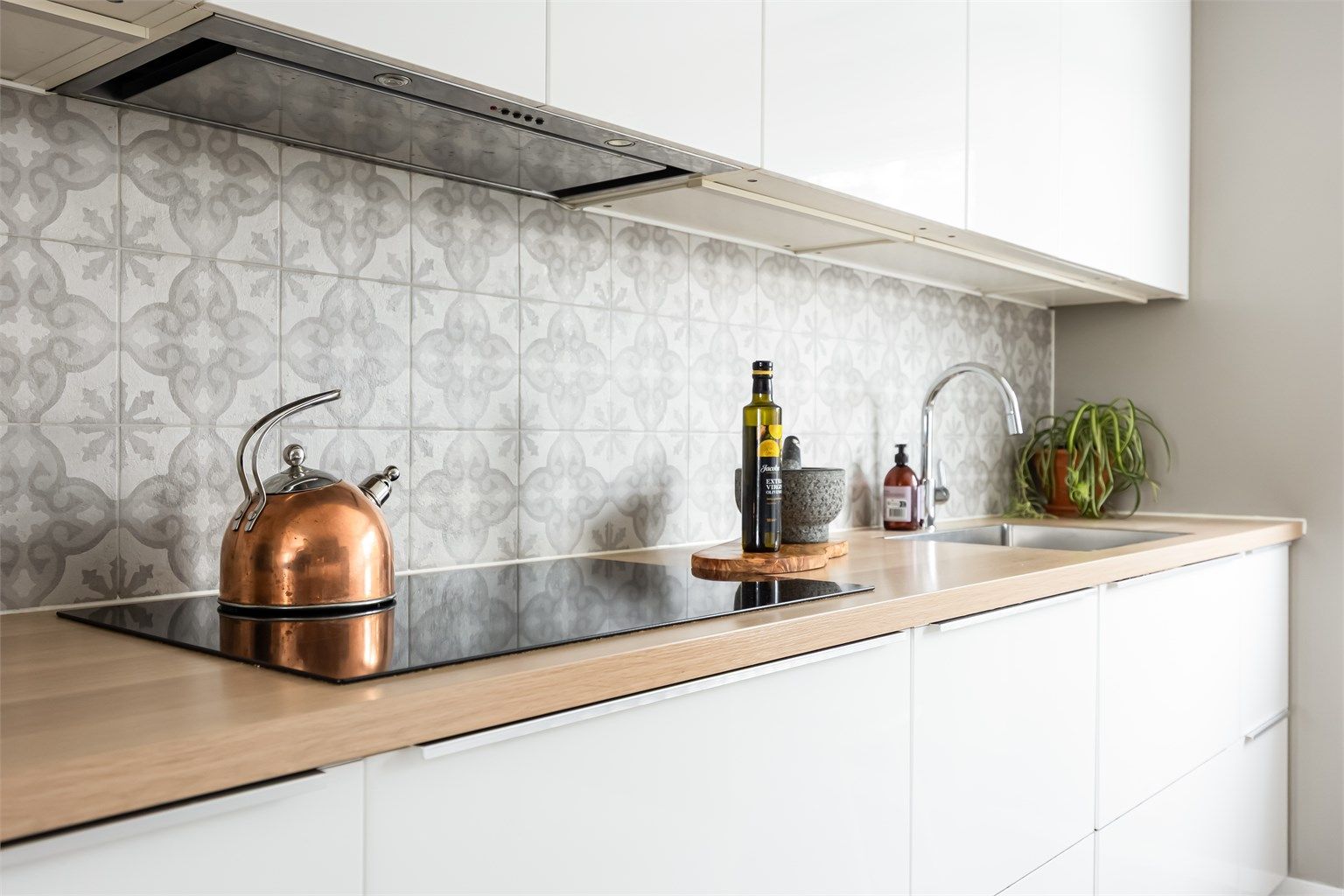 Kjøkkenet har laminat benkeplater, flislagt vegg over benk og benkeskapbelysning.