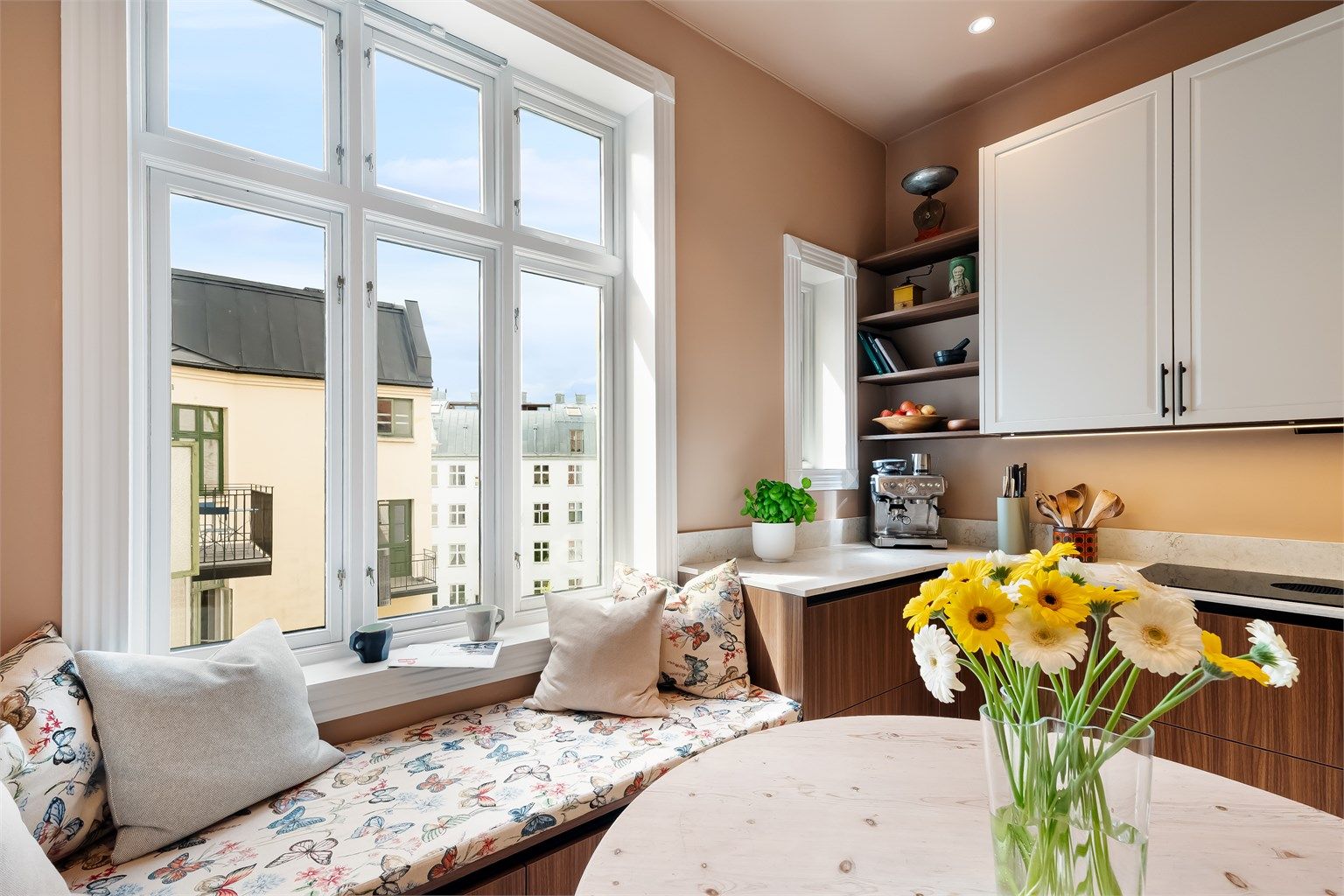 Vinduet mot bakgården slipper inn godt med naturlig lys og den plassbygde sittekroken langs veggen egner seg til hyggelige måltider og koselige stunder med en tekopp i vindukarmen.