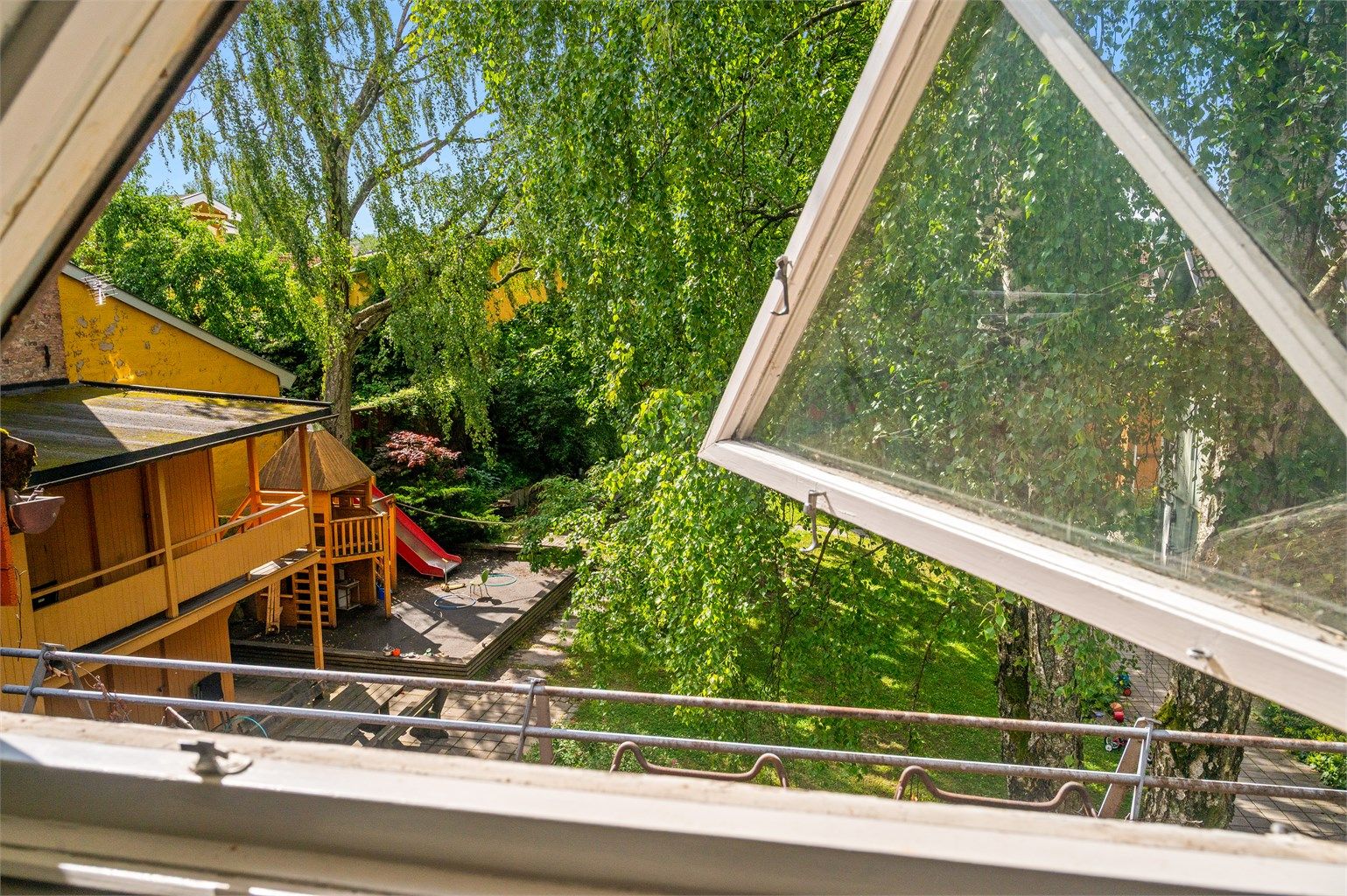 Utsikt fra vinduet mot det grønne og frodige fellesområdet.