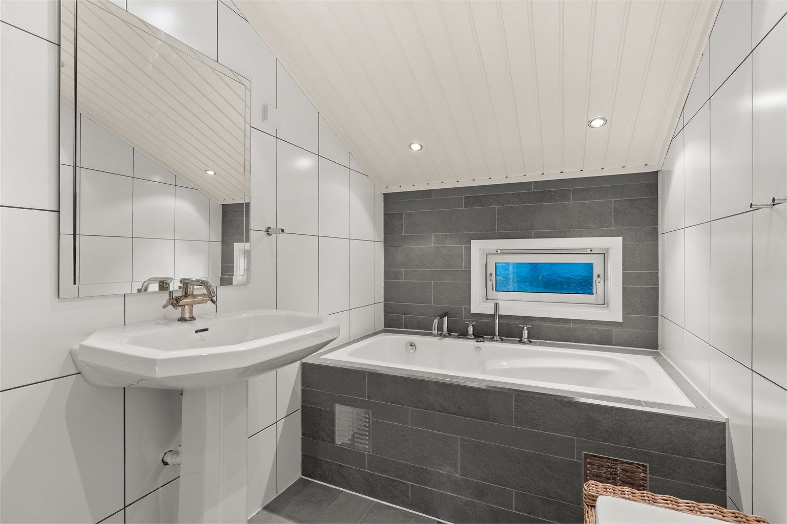 Badet i loftsetasjen er utstyrt med innfliset badekar og downlights i himlingen.