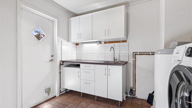 Vaskerom vurdert til å være fra byggeår. Flislagt gulv og vegger med panelplater, malt glatt flate samt malt mur/murpuss. Himling med panel.