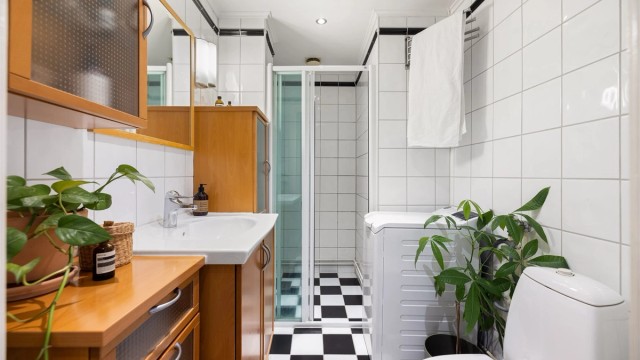 Flislagt baderom med gulvvarme, downlights og praktisk opplegg for vaskemaskin.