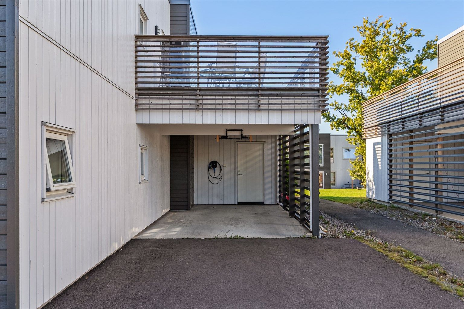 Tilhørende carport med montert elbillader fra 2025 og ekstern bod.
