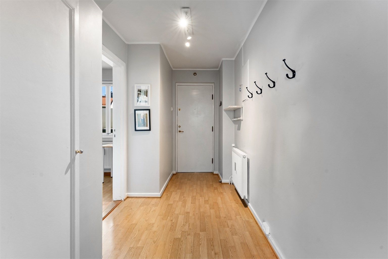 Velkommen inn i en lys entré med plass til å henge fra seg yttertøy.