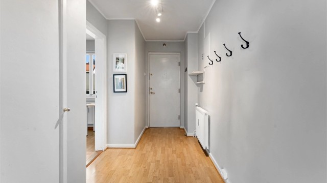 Velkommen inn i en lys entré med plass til å henge fra seg yttertøy.