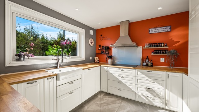 Stor porselensvask, benkeplate i heltre og den luftige løsningen med mye skapplass gir kjøkkenet et landlig preg.