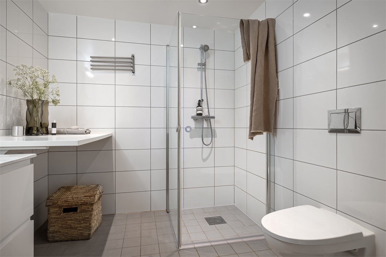 Badet er utstyrt med vegghengt toalett og dusjhjørne med innfellbare glassdører