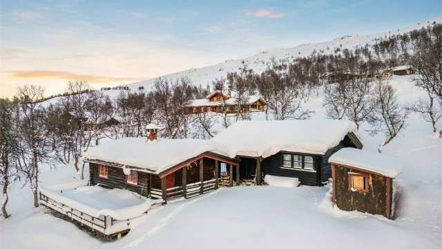 Tomta ligger høyt og fint i terrenget, omgitt av et vakkert fjellandskap.