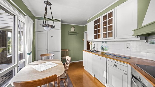 Kjøkkeninnredning med profilerte fronter, vitrineskap og oppvaskkum i stål.