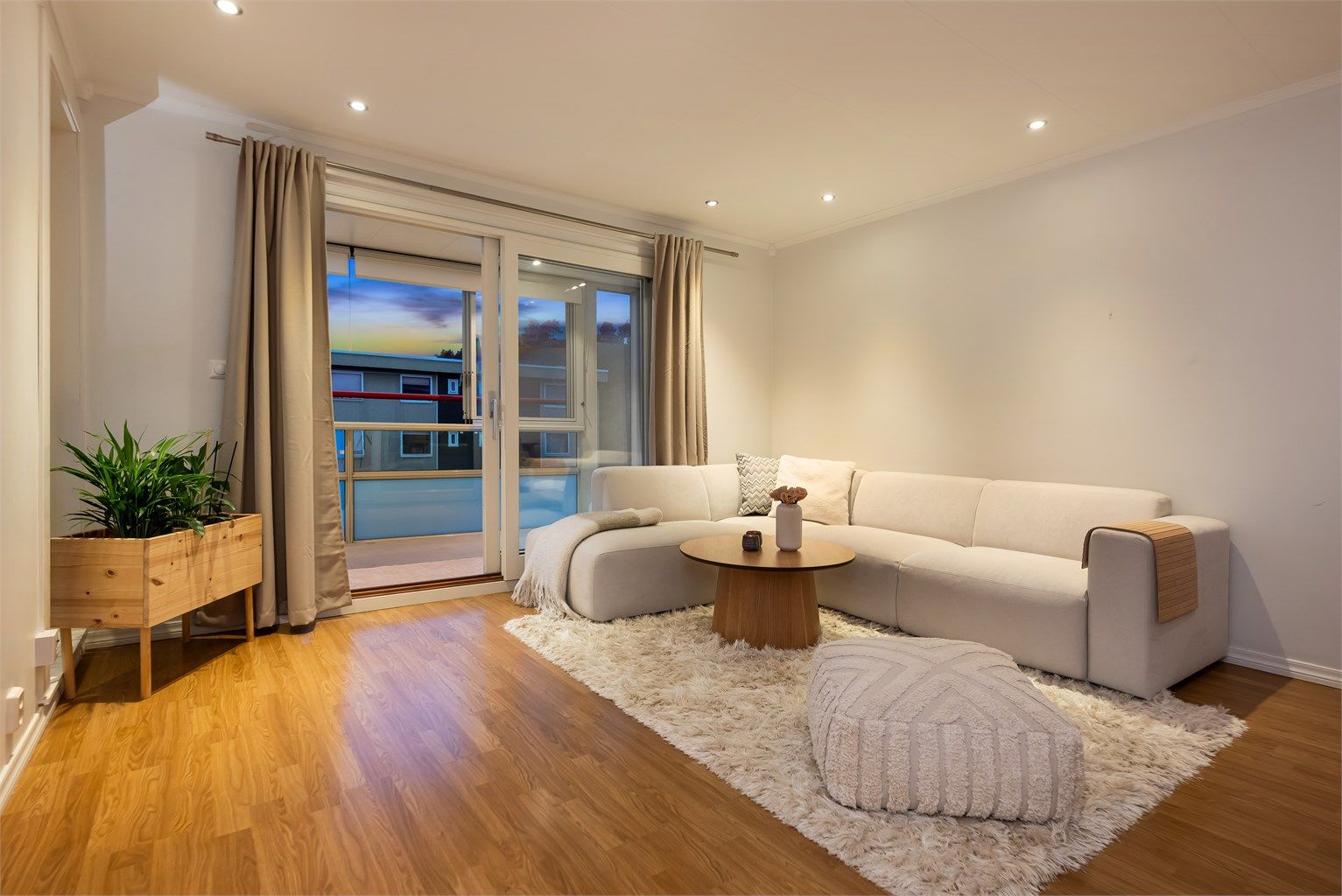 Stue med downlights i tak og store vindusfelt som gir godt lys til rommet.