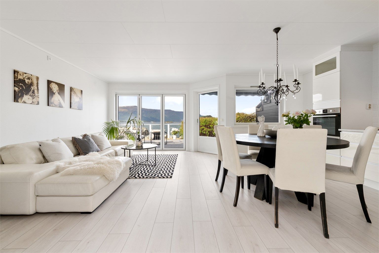 Stue og kjøkken i åpen løsning med store vindusflater som gir godt med naturlig lysinnslipp i boligen