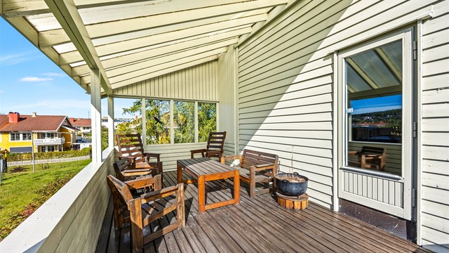 Overbygd terrasse med spaltegulv i treverk og god plass til utemøbler.