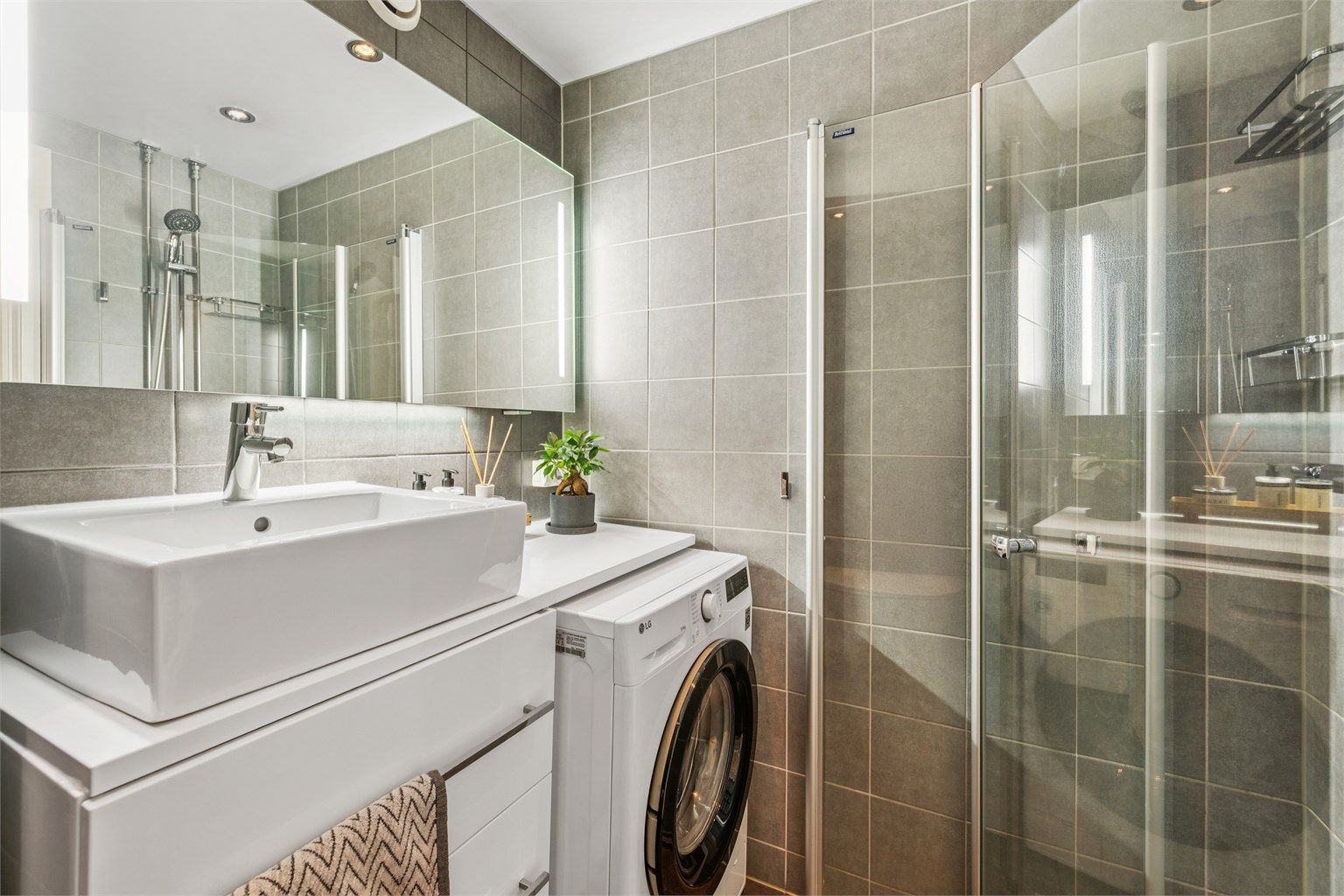 Badet er utstyrt med vegghengt toalett, dusjhjørne med innfellbare dører og opplegg for vaskemaskin.