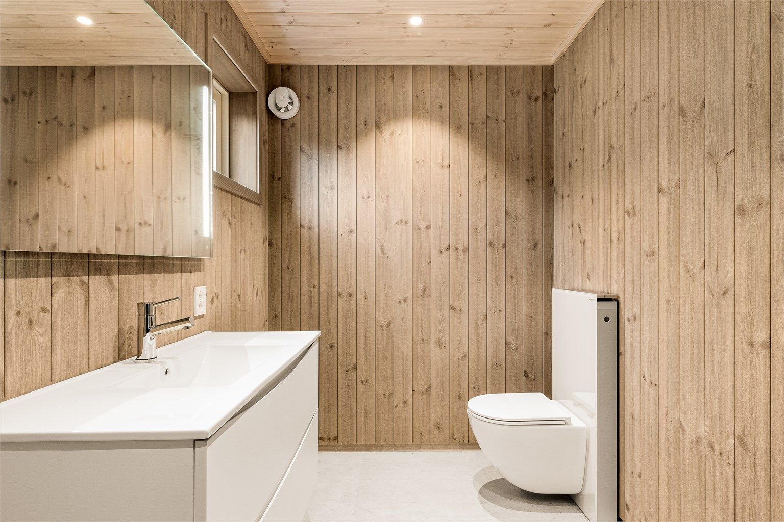 Badet er enkelt og tidløst, flisene med gråsjattering står fint til den enkel baderomsinnredningen.
