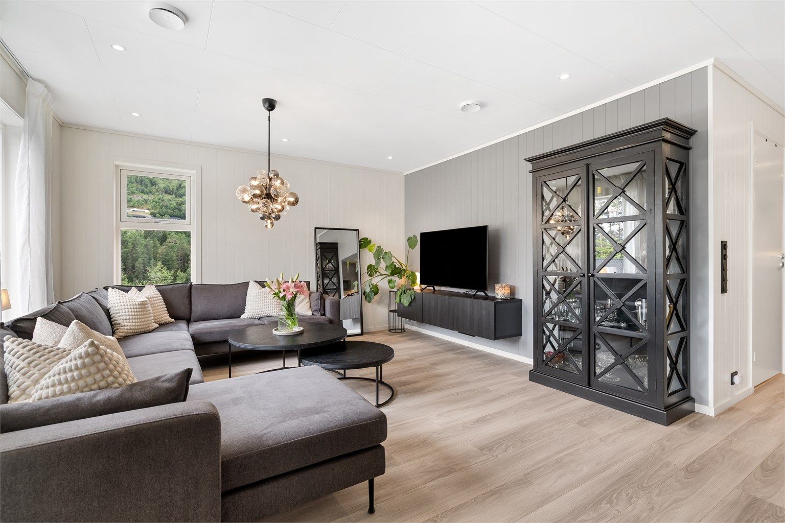 Videre fra gangen kommer man inn i et åpent og luftig stue-kjøkkenrom med lyse overflater og spotter i innvendig tak