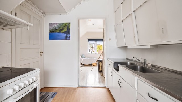Kjøkkeninnredning med glatte fronter og benkeplate av rustfritt stål med nedfelt oppvaskkum.