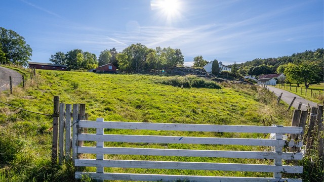 Gjerdestolper og grind rammer inn eiendommens naturskjønne utearealer.