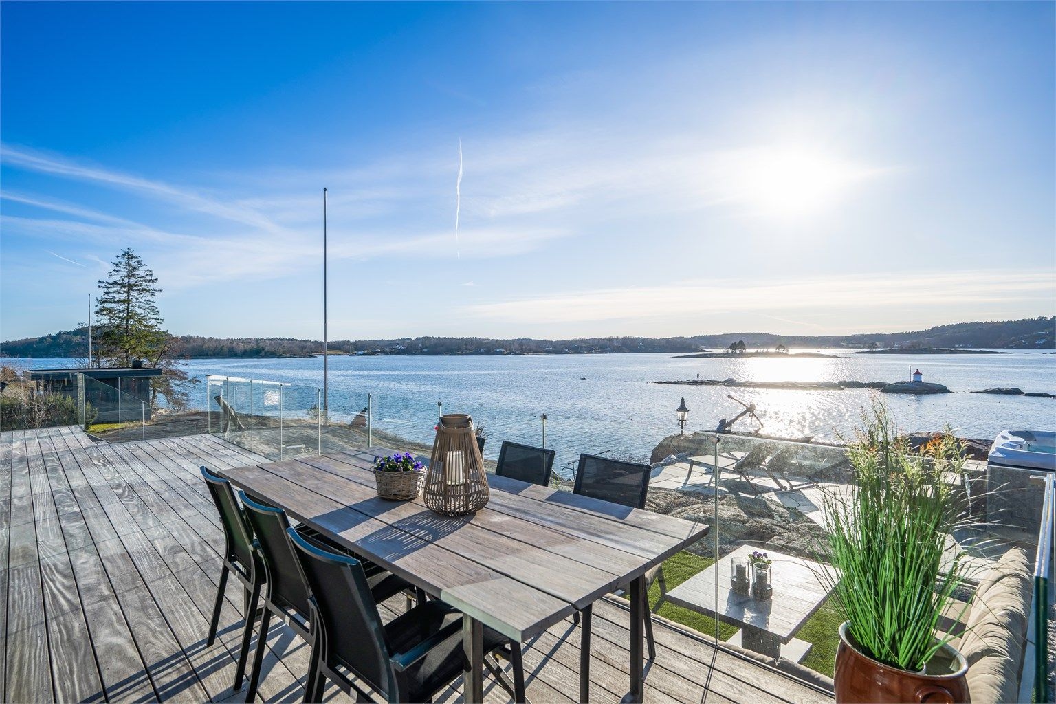 Utgang fra stue og spisestue i 1. etasje via store skyvedører til vestvendt terrasse oppført med vedlikeholdsvennlig tredekke og rekkverk i glass.