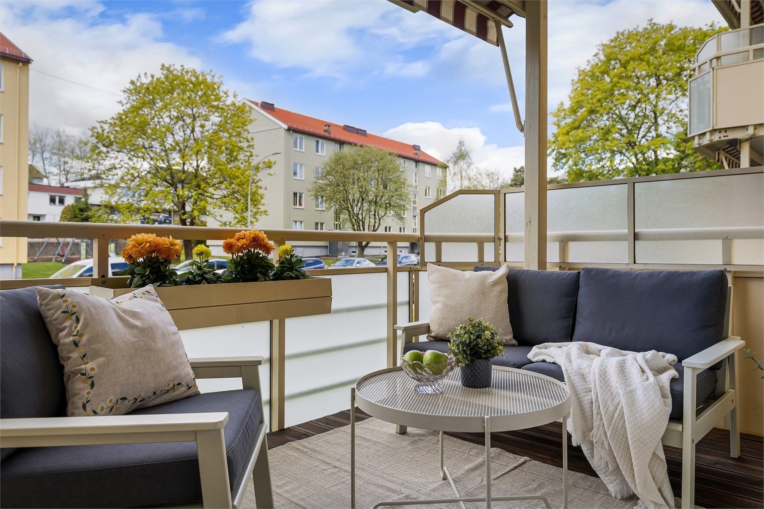 Tilfarer av tre med terrassebord. Rekkverk av stålkonstruksjoner med frostede glassfelt. Rekkverkshøyden ble målt til: 1,02 m. Elektrisk markise over balkongen