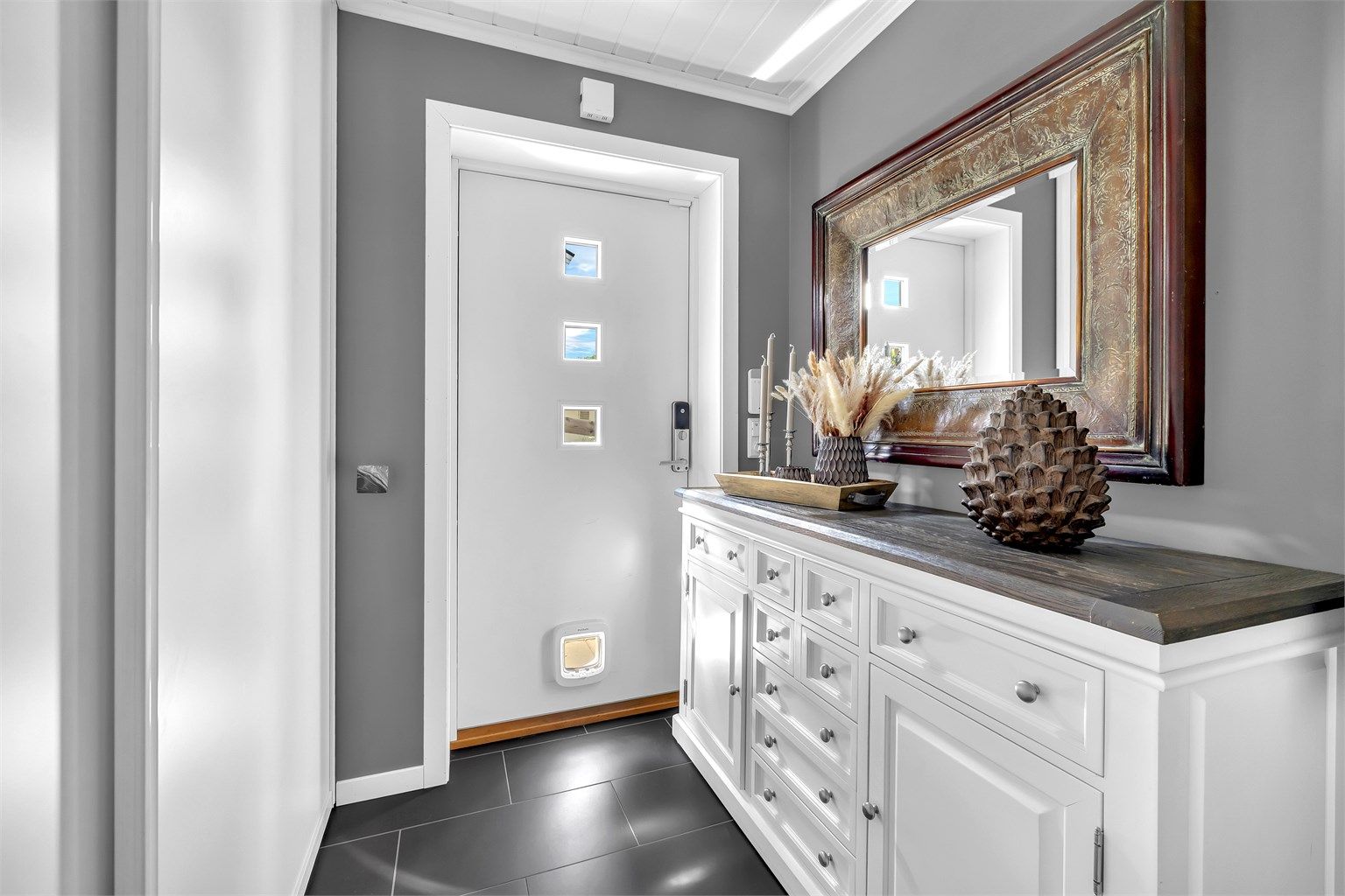 Du blir ønsket velkommen i en fin entré med grå fliser på gulv med gulvvarme. Her er det godt med plass for å henge fra deg ytterklær og sko, samt godt med lagringsplass i montert skyvedørsgarderobe. 