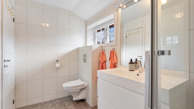 Badet er utstyrt med vegghengt toalett, innredning med skuffer og dusjløsning med regnfallsdusj.