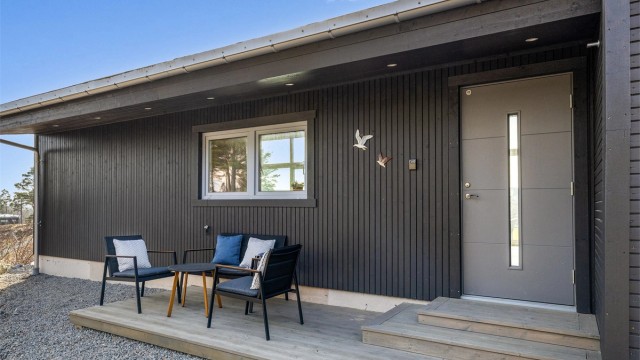 BAKSIDE MED STIL: Fra inngangspartiet ser du tvers gjennom hytta og ut mot sjøen. Her er det også anlagt en liten terrasse for morgensolen.