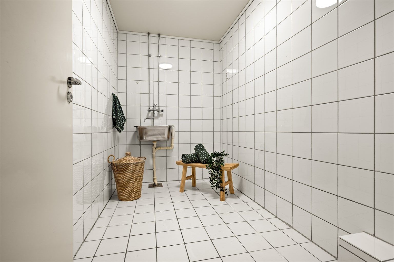 Leiligheten har et separat og praktisk vaskerom med flislagte overflater, utslagsvask og opplegg for vaskemaskin.