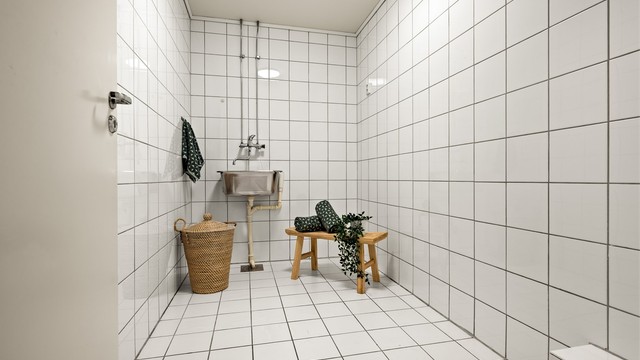 Leiligheten har et separat og praktisk vaskerom med flislagte overflater, utslagsvask og opplegg for vaskemaskin.