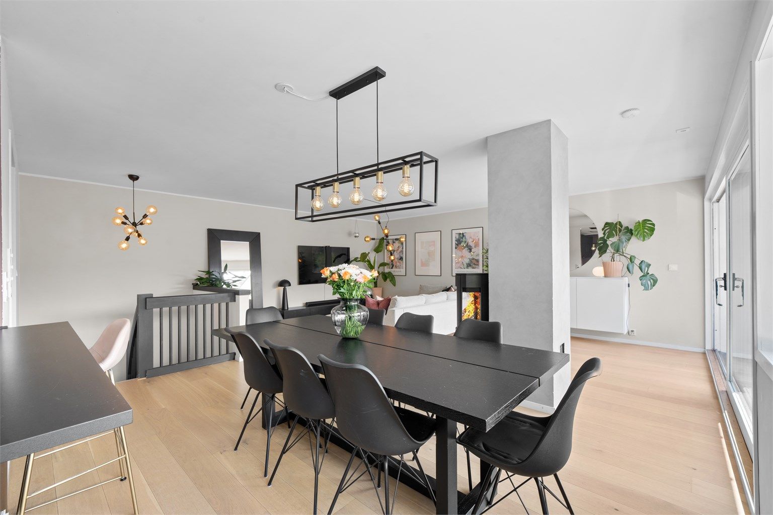 Stue/spisestue sett fra kjøkken. Gjennomgående luftig følelse med peisen som rommets midtpunkt 